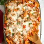 Baked stuffed pepper pasta in a dish with melted cheese and fresh herbs