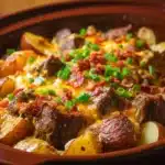 Crockpot Loaded Steak and Potato Bake dish served in a bowl with garnish.