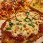 Plate of crispy chicken parmesan with marinara sauce and melted cheese